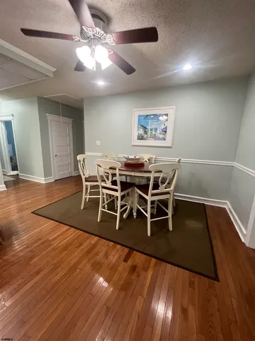 a dining room with wooden floor a chandelier a glass table and chairs