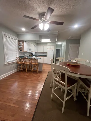 a dining room with wooden floor a chandelier a glass table and chairs