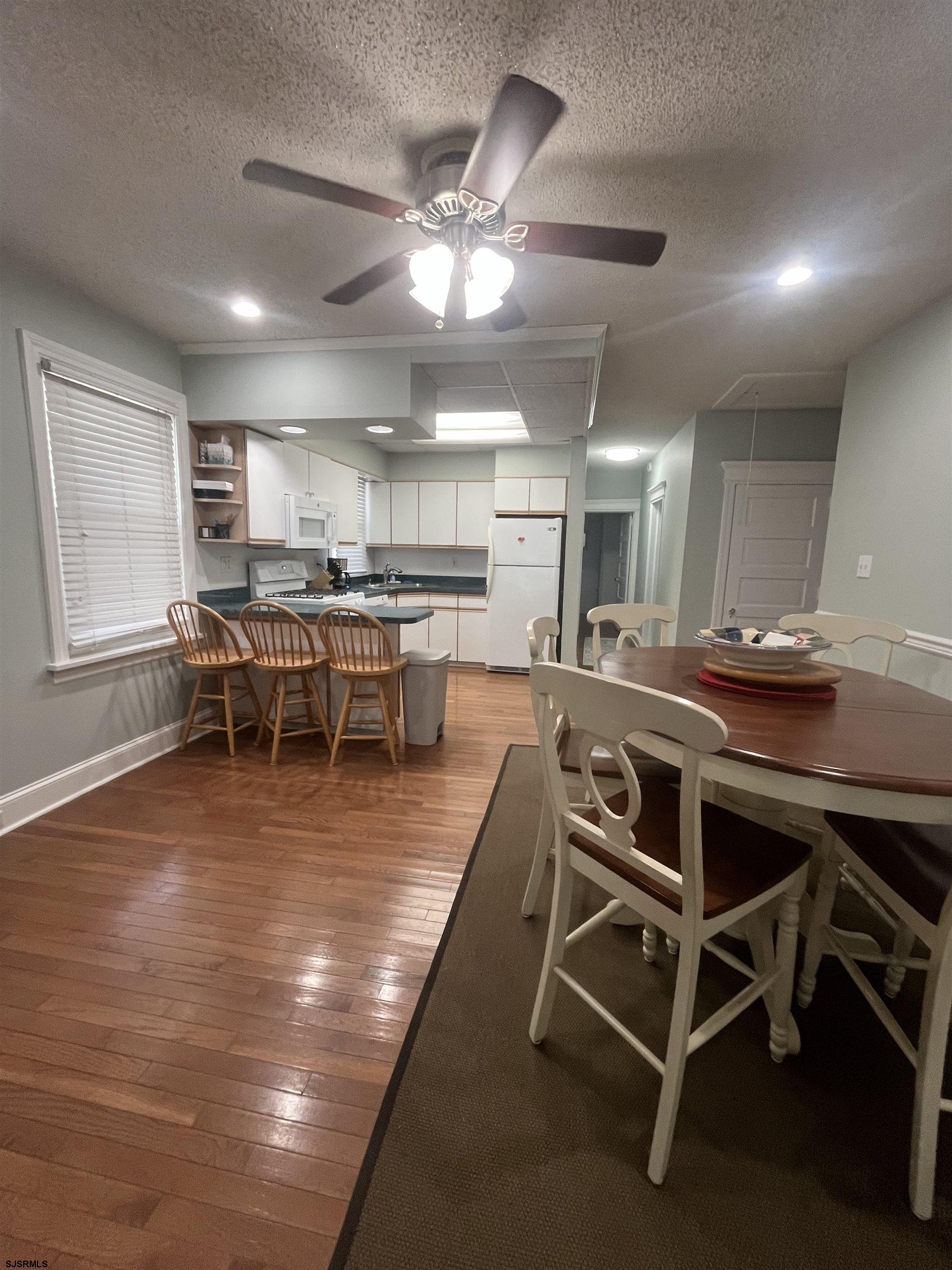 15 North Melbourne Avenue, Unit WINTER 2025 Ventnor City, NJ 08406 - Photo 7 of 15 a dining room with wooden floor a chandelier a glass table and chairs