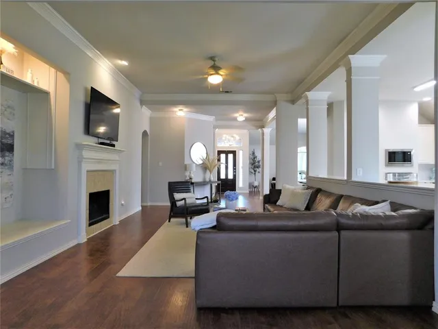 a living room with furniture a fireplace a flat screen tv and kitchen view