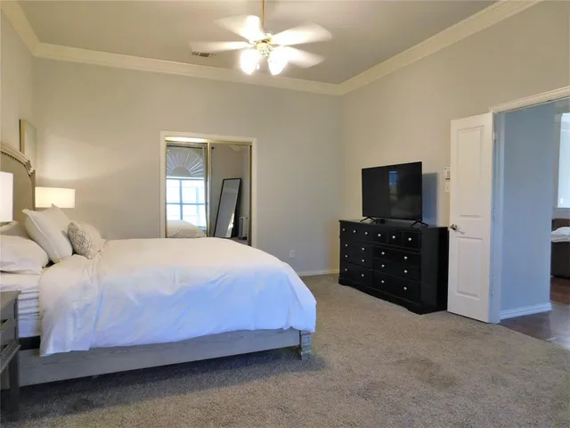 a bedroom with a bed and a flat tv screen on dresser