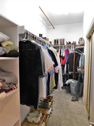 a view of walk in closet with clothes and shoes