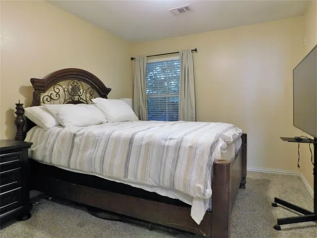 a bedroom with a bed and a flat tv screen on the dresser