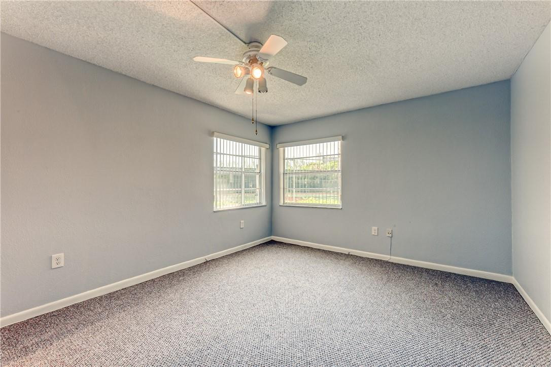 3900 Inverrary Boulevard, Unit E2 Lauderhill, FL 33319 - Photo 32 of 45 an empty room with a chandelier fan and windows