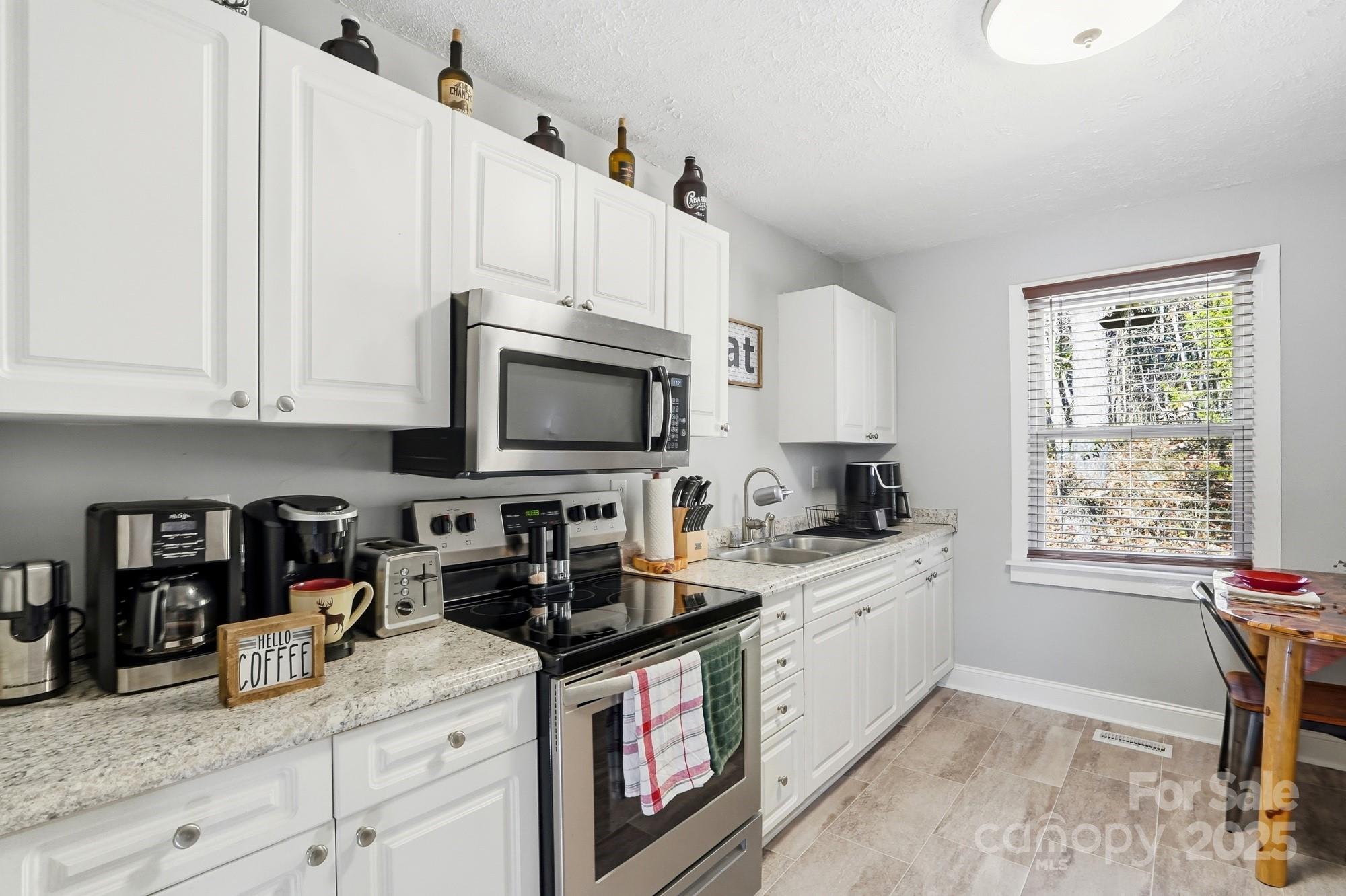 910 Roosevelt Street Badin, NC 28001 - Photo 20 of 30 a kitchen with granite countertop a stove a sink and a microwave