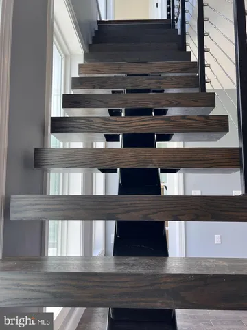 a view of an empty room with wooden floor fan and windows