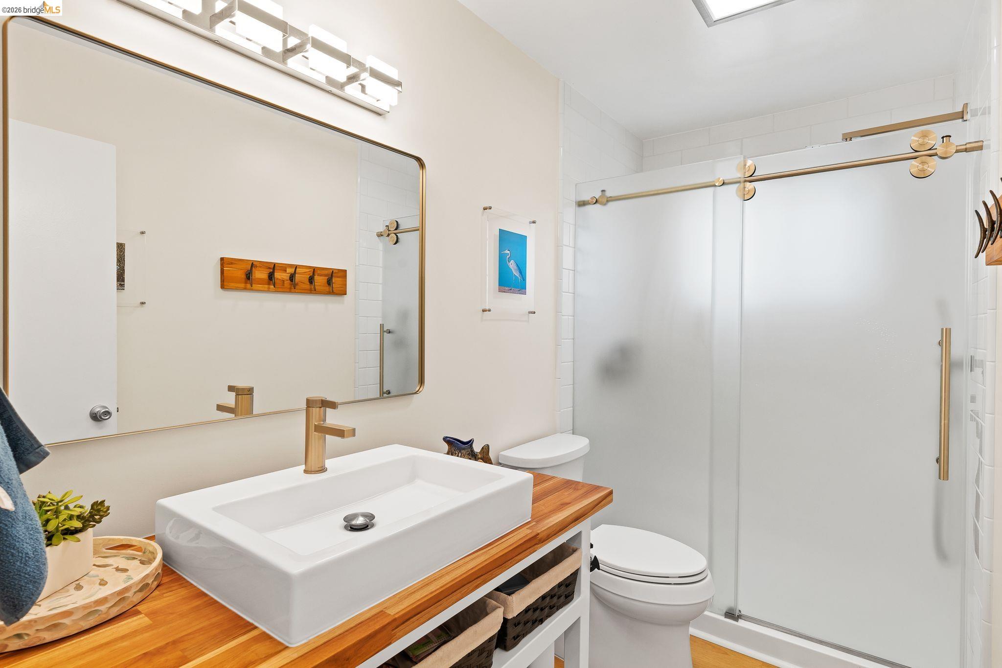 1704 Taylor Road Bethel Island, CA 94511 - Photo 40 of 73 Bathroom featuring a rectangular vessel sink with a gold-tone faucet, wood-finish countertop, and a shower with frosted sliding glass doors and gold-tone hardware