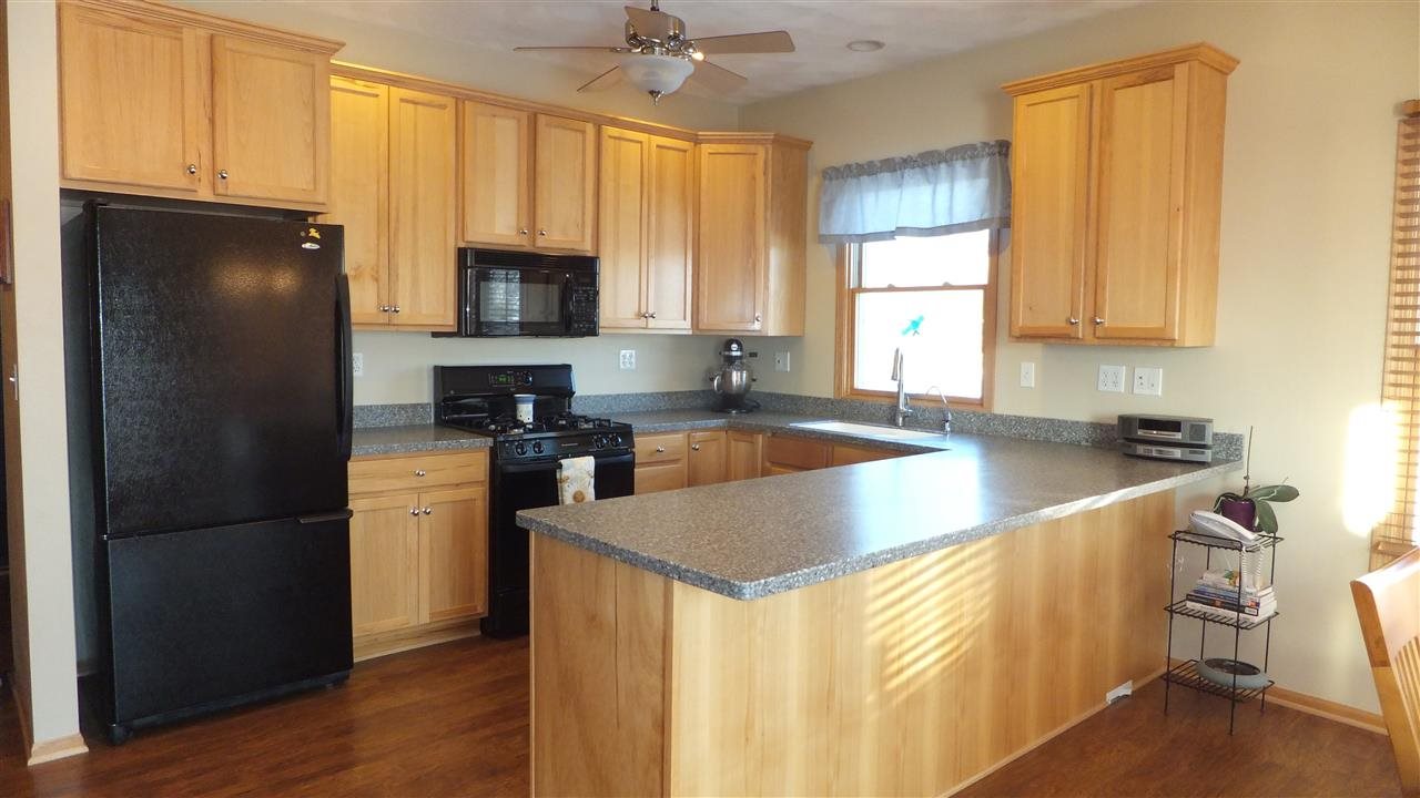 2835 Dourdan Road Belvidere, IL 61008 - Photo 7 of 25 a kitchen with granite countertop a refrigerator a sink a stove a microwave and wooden cabinets