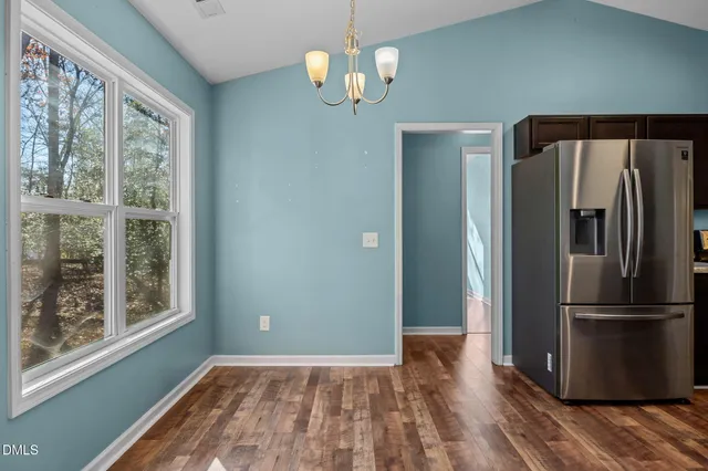 a view of a kitchen with wooden floor refrigerator and windows