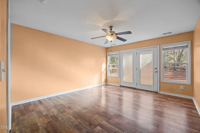 a view of an empty room with a window and wooden floor