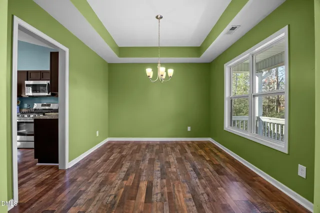 a view of an empty room with window and wooden floor