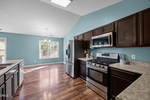 a kitchen with stainless steel appliances kitchen island granite countertop a stove a sink and a microwave