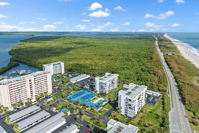 an aerial view of ocean and residential houses with outdoor space