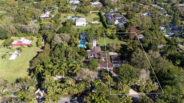 an aerial view of residential houses with outdoor space and trees