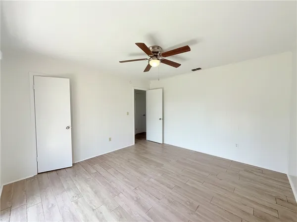 a view of a big room with wooden floor and a ceiling fan