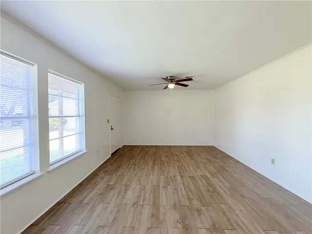 an empty room with wooden floor and windows