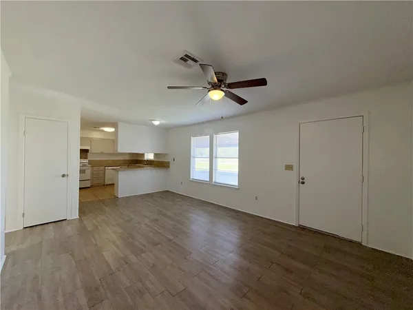 a view of an empty room with a kitchen and wooden floor