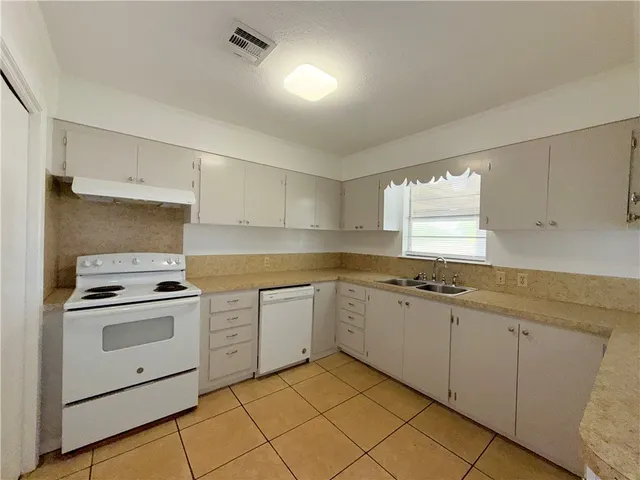a kitchen with white cabinets appliances and a sink