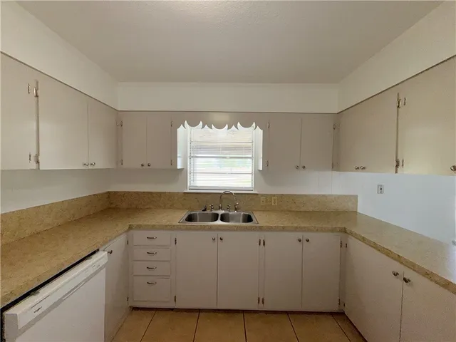 a kitchen with granite countertop white cabinets and window