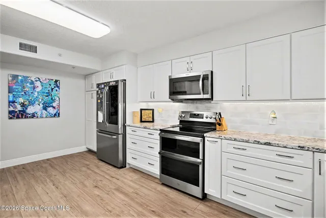 a kitchen with granite countertop a refrigerator stove and wooden floor