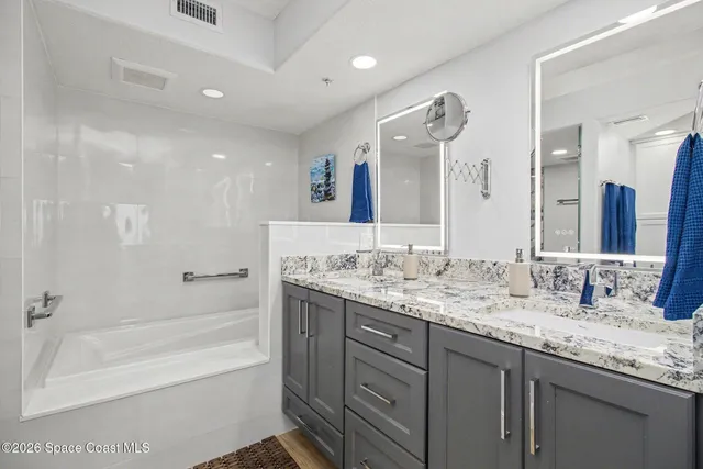 a bathroom with a granite countertop sink mirror and a bath tub