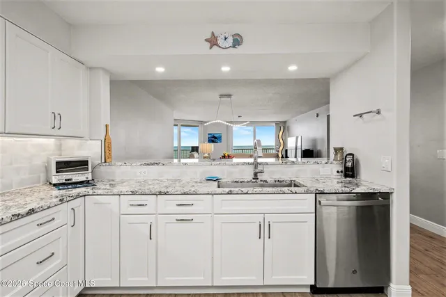 a kitchen with granite countertop a sink stainless steel appliances and white cabinets