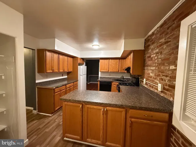 a kitchen with stainless steel appliances granite countertop a refrigerator a stove and a sink with wooden floor