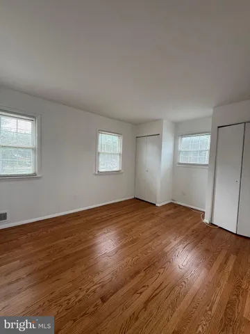 a view of an empty room with wooden floor and window