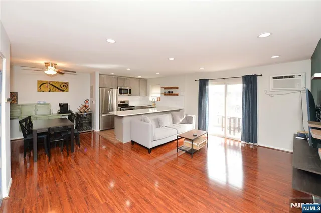 a living room with stainless steel appliances kitchen island hardwood floor and a view of kitchen