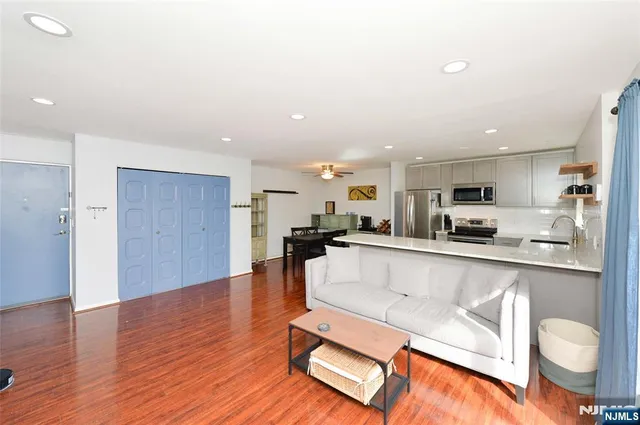 a living room with stainless steel appliances kitchen island granite countertop a living room view and wooden floor