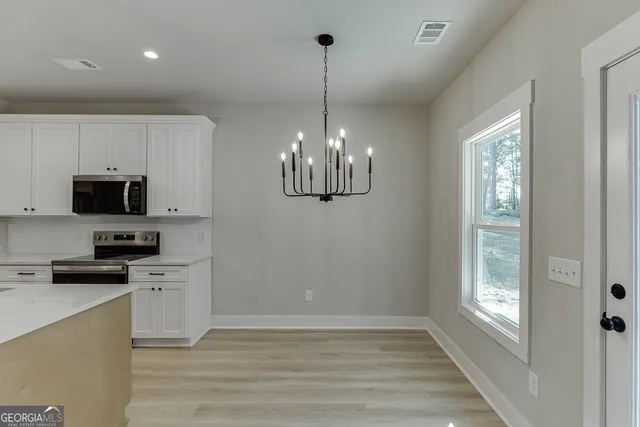 a kitchen with stainless steel appliances granite countertop a refrigerator a sink dishwasher a stove and white cabinets with wooden floor