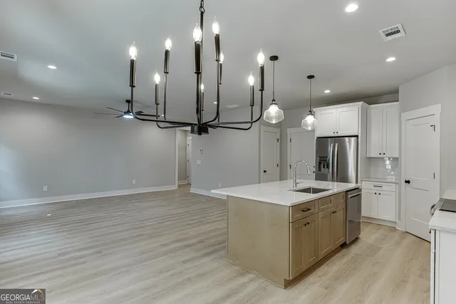 a kitchen with a sink chandelier and refrigerator