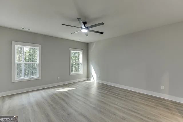 a view of an empty room with a window and wooden floor
