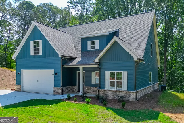a view of a house with a yard plants and large tree
