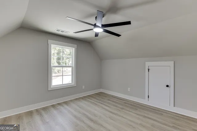 an empty room with wooden floor closet and windows