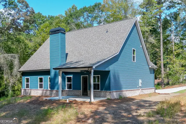 a view of a house with a yard plants and large tree