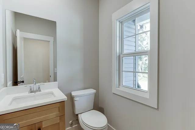 a bathroom with a granite countertop sink toilet a mirror and window