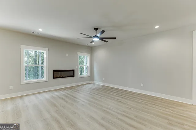 an empty room with ceiling fan and windows