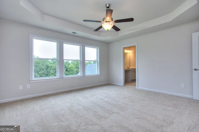 an empty room with windows and fan