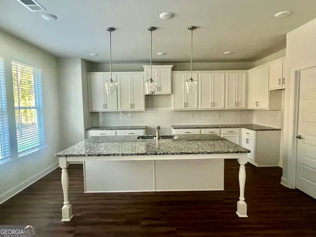 a kitchen with kitchen island granite countertop a sink cabinets and stainless steel appliances