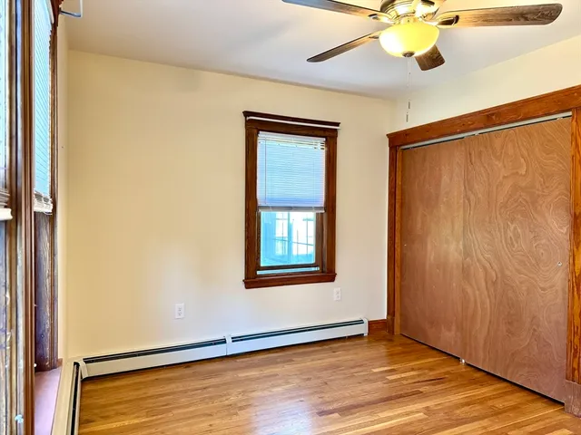 an empty room with wooden floor fan and windows