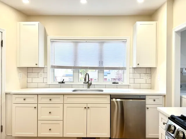 a kitchen with granite countertop white cabinets and a window
