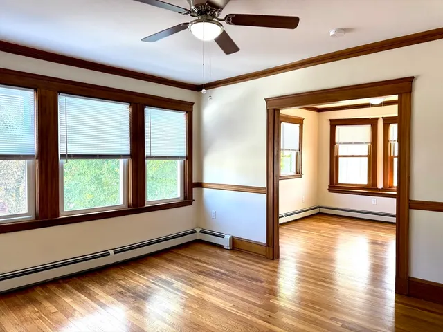 a view of an empty room with wooden floor and a window