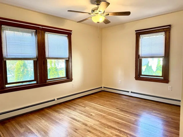 a view of an empty room with a window and wooden floor