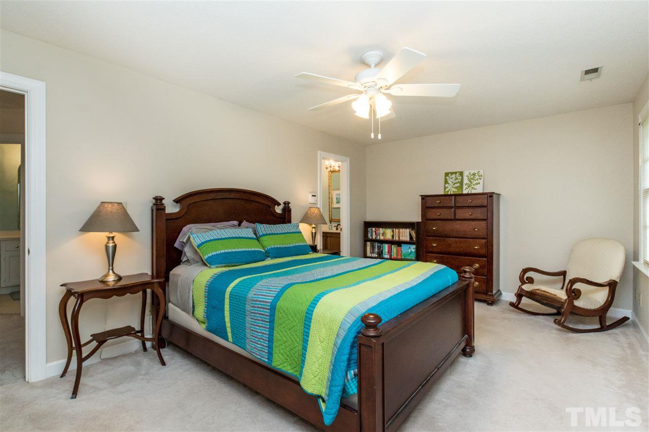 10828 Cahill Road Raleigh, NC 27614 - Photo 14 of 25 a bedroom with a bed a chair and a chandelier