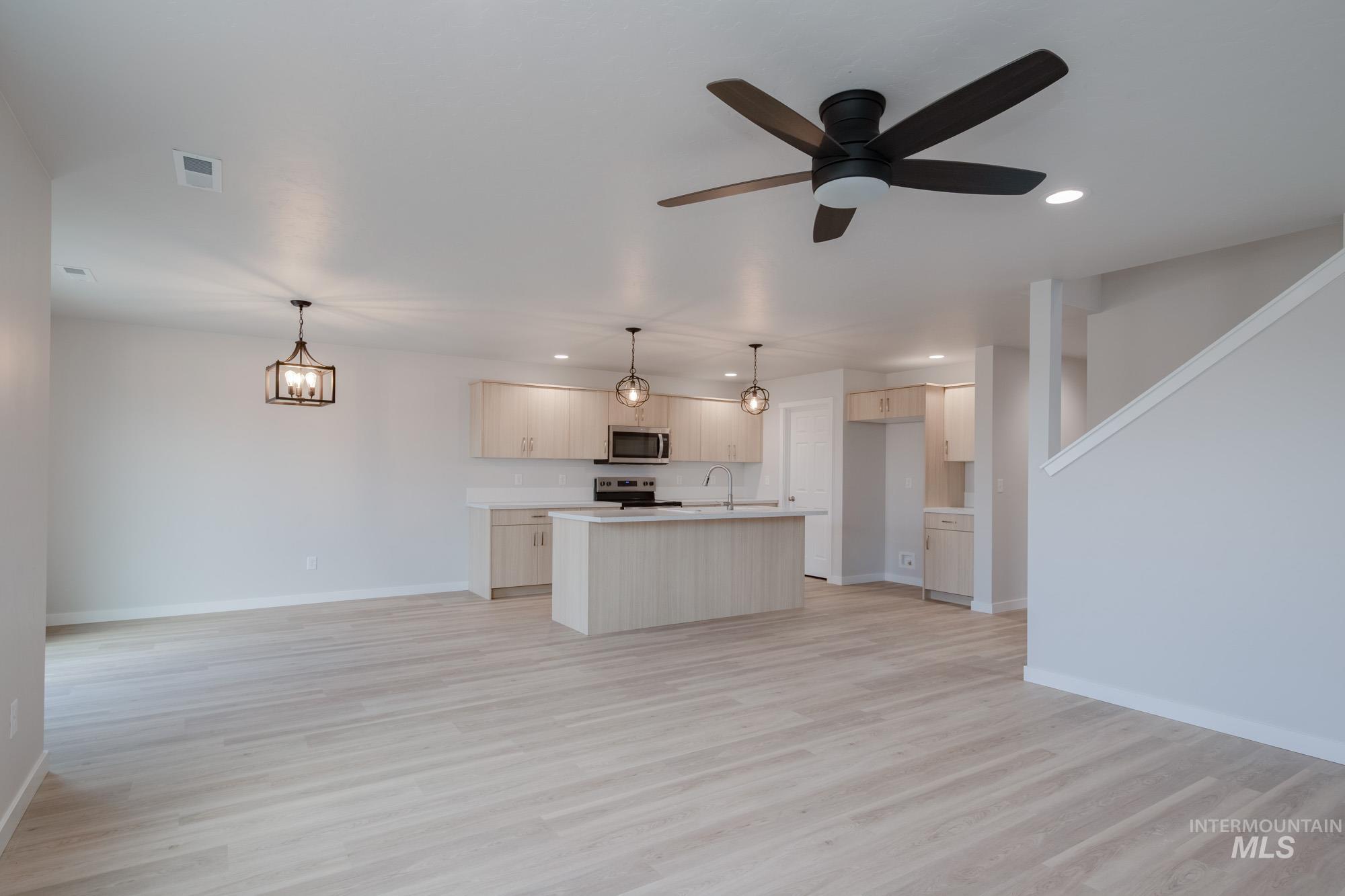 3089 South Maple Rnch Way Nampa, ID 83686 - Photo 22 of 22 Kitchen with open floor plan, light countertops, a kitchen island with sink, recessed lighting, and decorative light fixtures