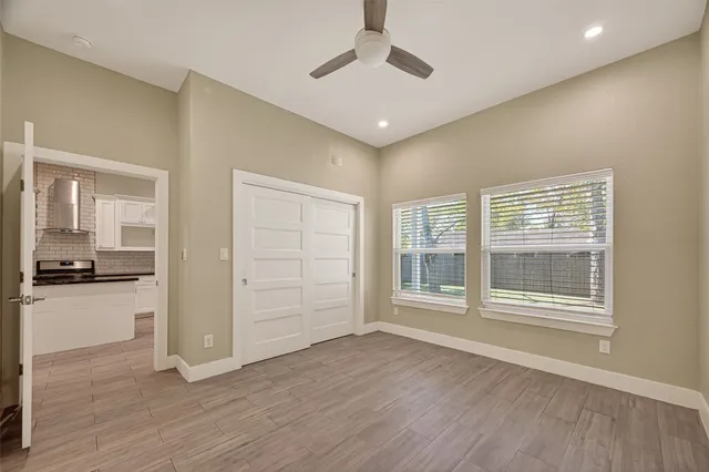 an empty room with wooden floor cabinet and windows