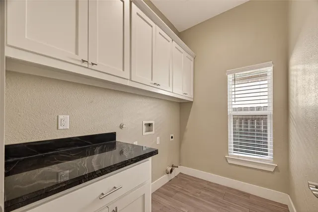 a kitchen with granite countertop white cabinets and a wooden floor