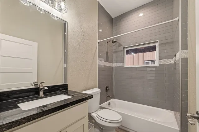 a bathroom with a granite countertop sink mirror toilet and bathtub