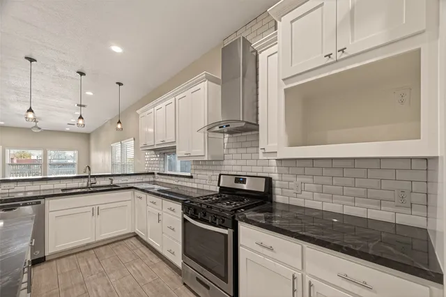 a white kitchen with stainless steel appliances granite countertop a sink and cabinets with wooden floor